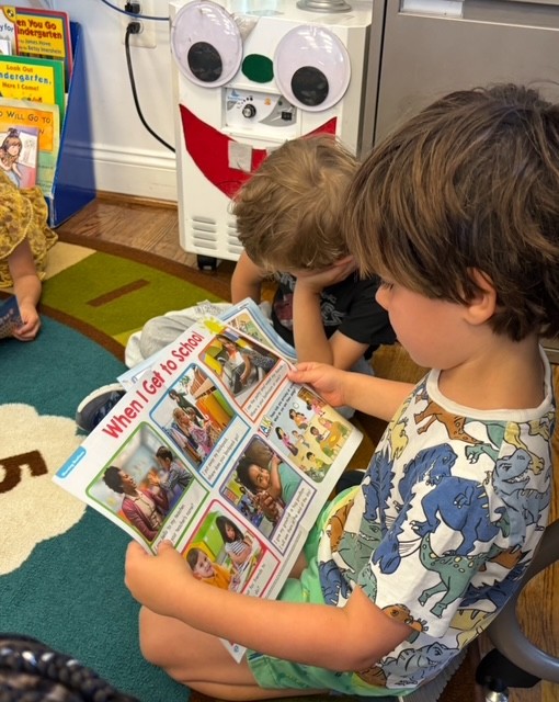 A child sits on a classroom floor and reads a book titled When I Get to School