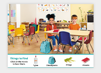 Two students sit at a desk in a colorful classroom with labeled items below
