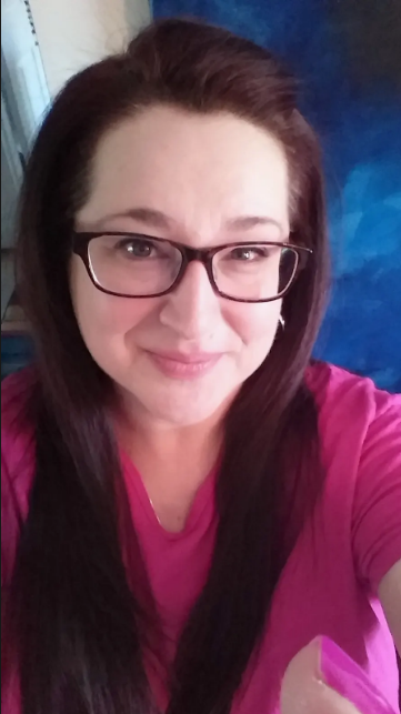 A woman with glasses and long dark hair faces the camera