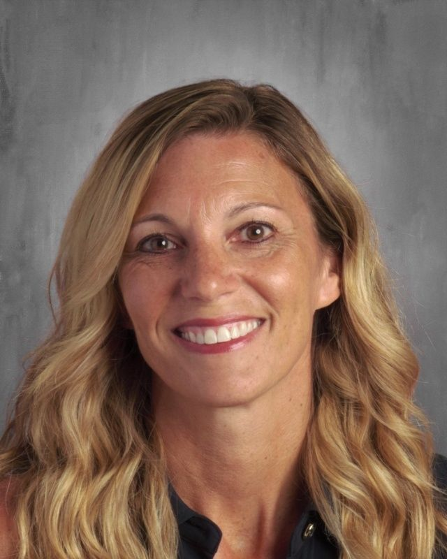 A woman faces the camera in a portrait against a gray background