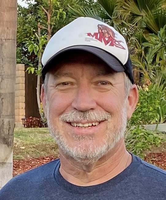 A man wears a baseball cap with the letters MMS in an outdoor setting
