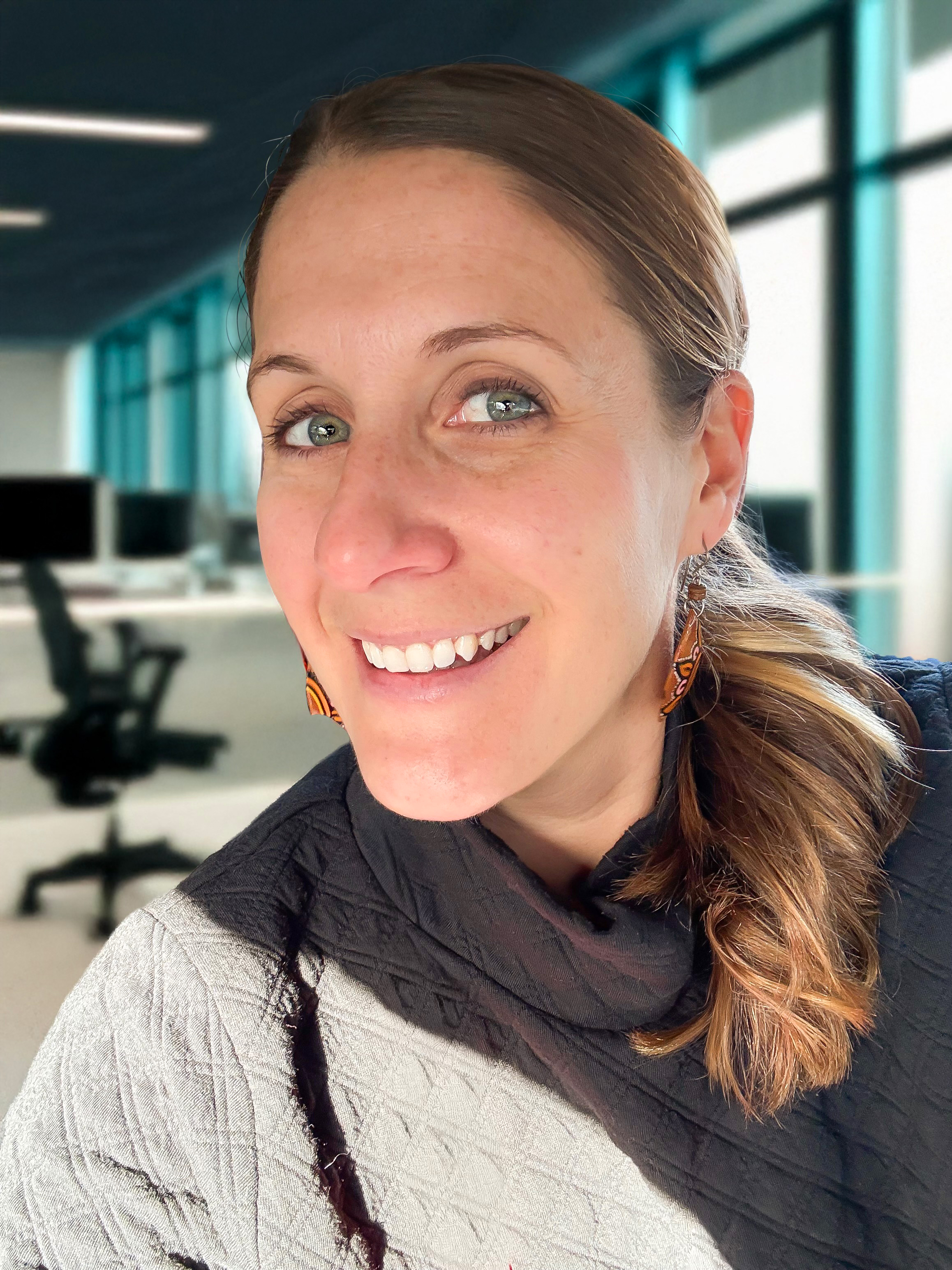 A woman faces the camera in an open office workspace
