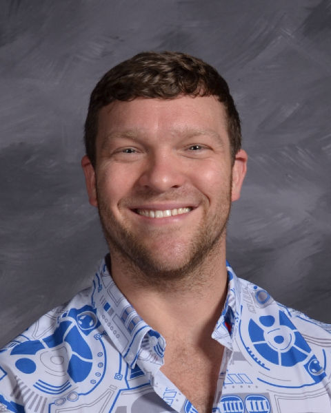 A man faces the camera in a portrait photo against a gray background